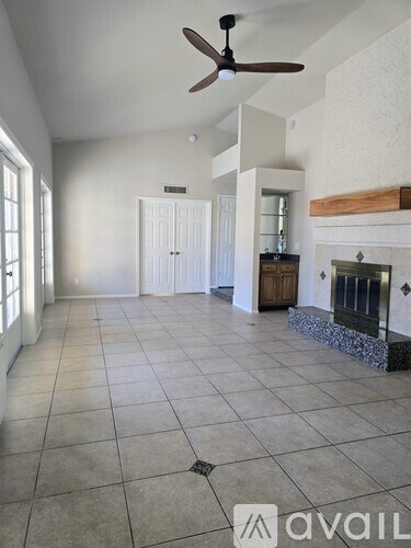 A spacious living room with a fireplace and a ceiling fan.