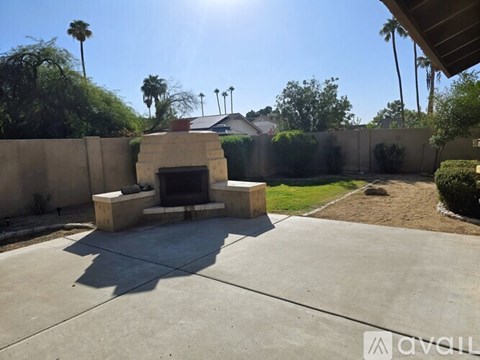 A backyard with a concrete patio and a fireplace.