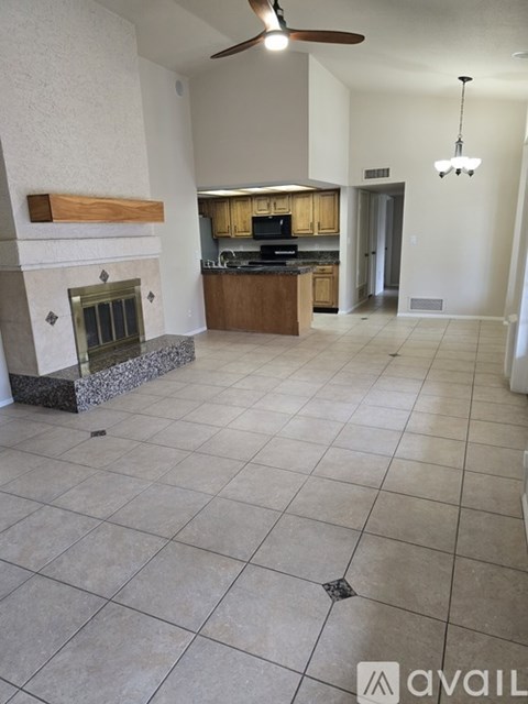 A living room with a fireplace and a kitchen in the background.