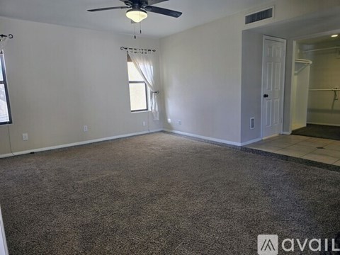 A room with a carpeted floor and a ceiling fan.