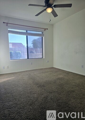 A room with a ceiling fan and a window with blinds.