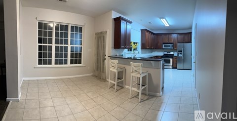 A kitchen with white chairs and a window with blinds.