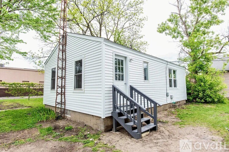 A small white house with a grey staircase leading to the door.