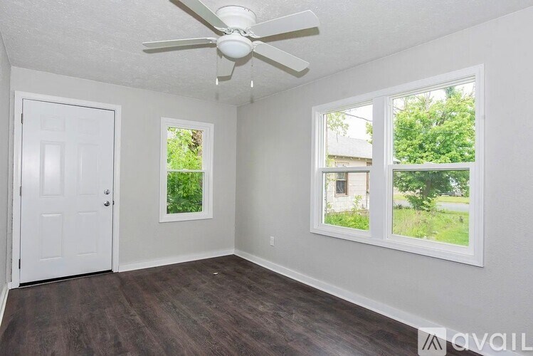 A room with a ceiling fan and two windows.