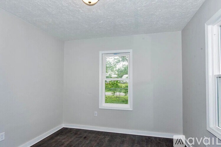 A room with a window and a wooden floor.