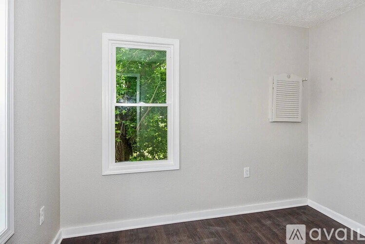 A room with a window and wooden flooring is available for rent.