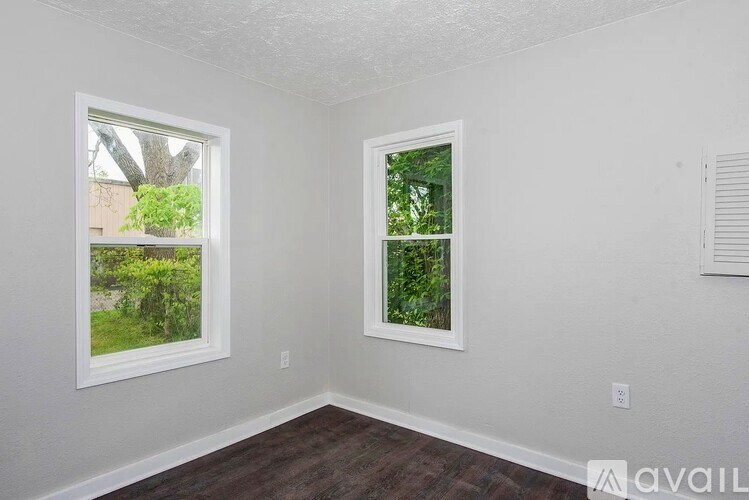 A room with two windows and a wooden floor.