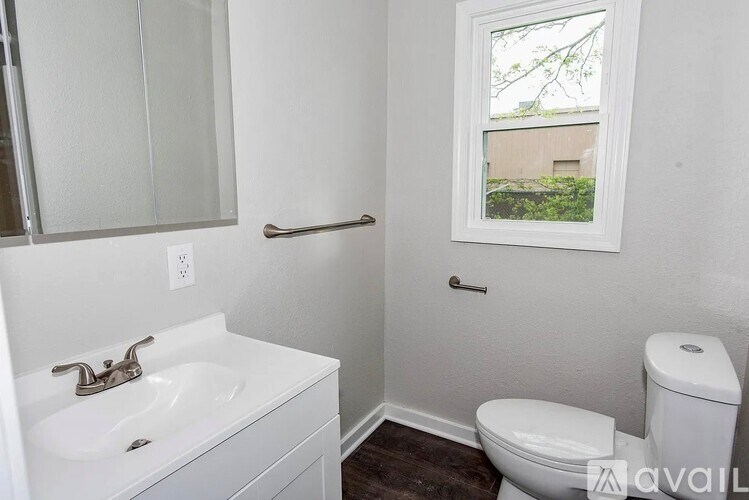 A bathroom with a toilet, sink, and mirror.