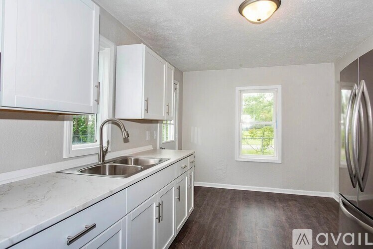 A kitchen with white cabinets and a marble countertop.