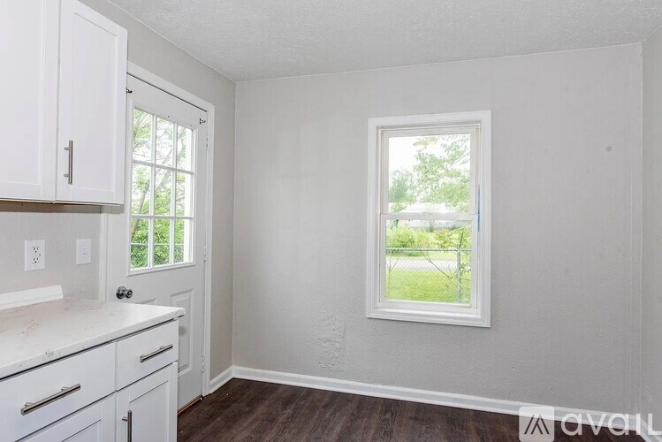 A kitchen with white cabinets and a window.