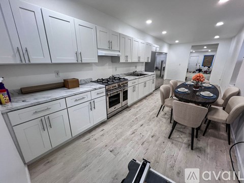 A kitchen with white cabinets and a dining table with chairs.