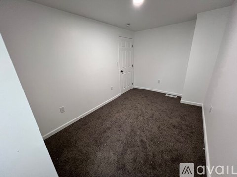 A room with a carpeted floor and a white door.