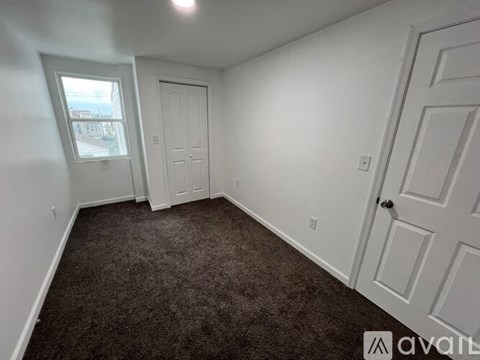 A room with carpeted floor, two doors, and a window.