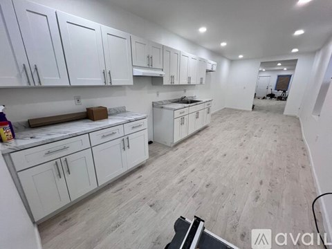 A kitchen with white cabinets and a wooden floor.