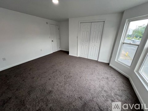 A room with a carpeted floor and two doors.