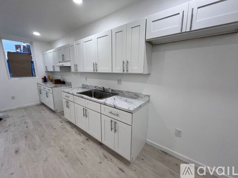 A kitchen with white cabinets and a marble countertop.