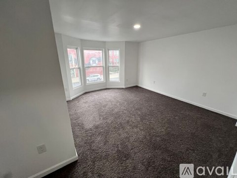 A room with a carpeted floor and a window overlooking a street.