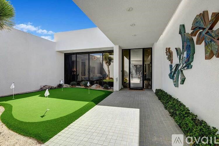 A modern house with a putting green in the backyard.