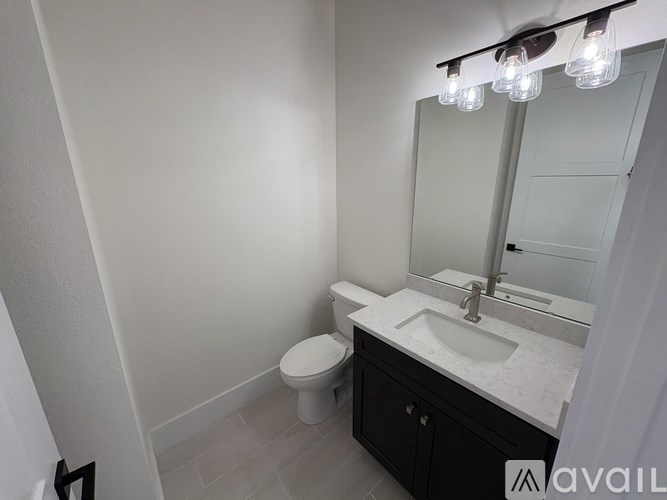 A bathroom with a toilet, sink, and mirror.