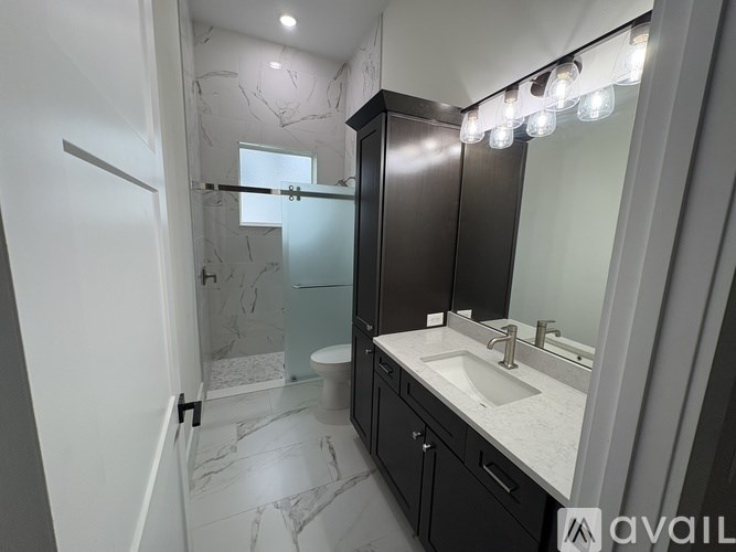 A bathroom with a marble floor and a vanity with a mirror and lights above it.