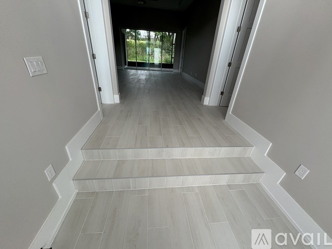 A hallway with wooden flooring and white walls.