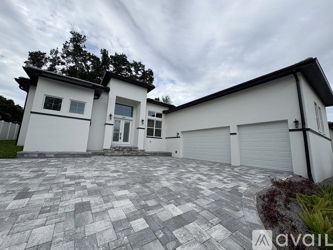 A modern two-story house with a white exterior and a large driveway.