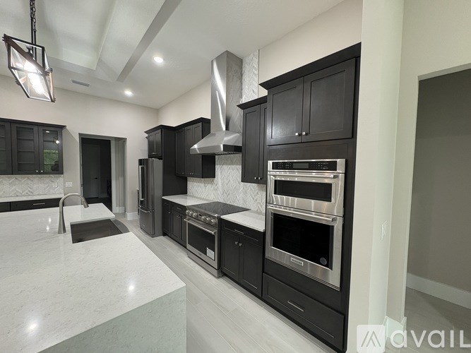 A modern kitchen with black cabinets and stainless steel appliances.