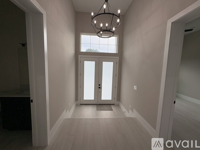 A well-lit, empty hallway with a chandelier and a large window.