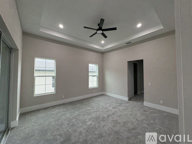 A spacious room with a ceiling fan and carpeted floor.