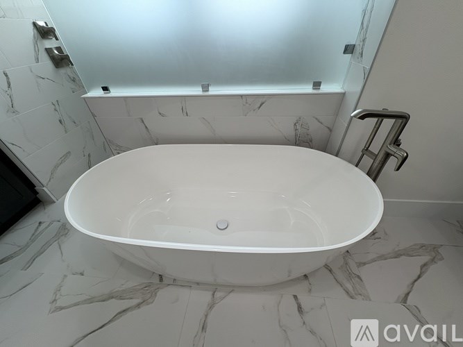 A white bathtub is placed on a marble floor.