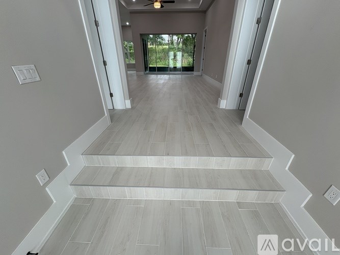 A hallway with wooden flooring and white walls.