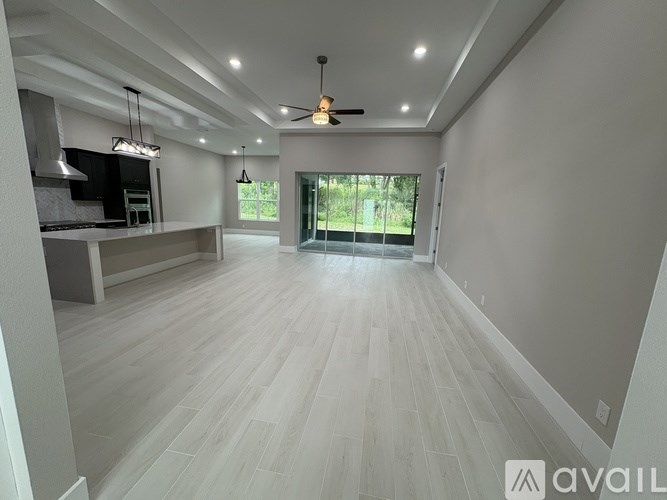 A spacious room with light wood flooring and a ceiling fan.