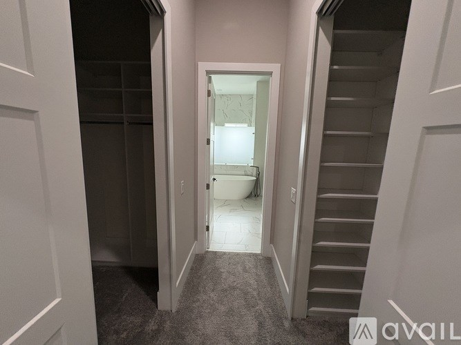 A hallway with a carpeted floor and a staircase on the right.