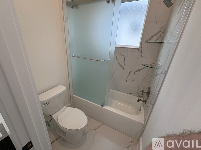A bathroom with a toilet, a bathtub and a glass shower door.