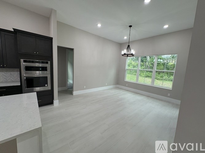 A modern kitchen with dark cabinets and a marble countertop.
