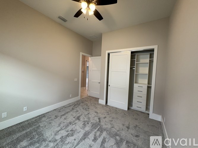 A room with a ceiling fan and a door leading to another room.