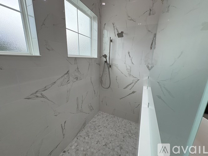 A bathroom with marble walls and a shower.