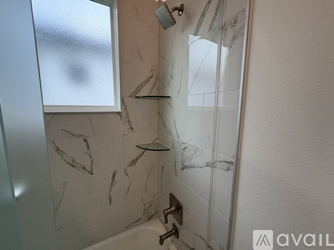 A bathroom with a marble wall and a shower.