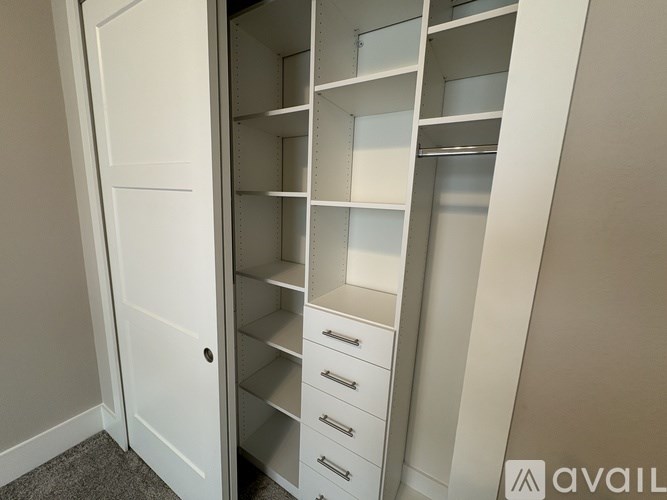 A white closet with shelves and drawers is open.