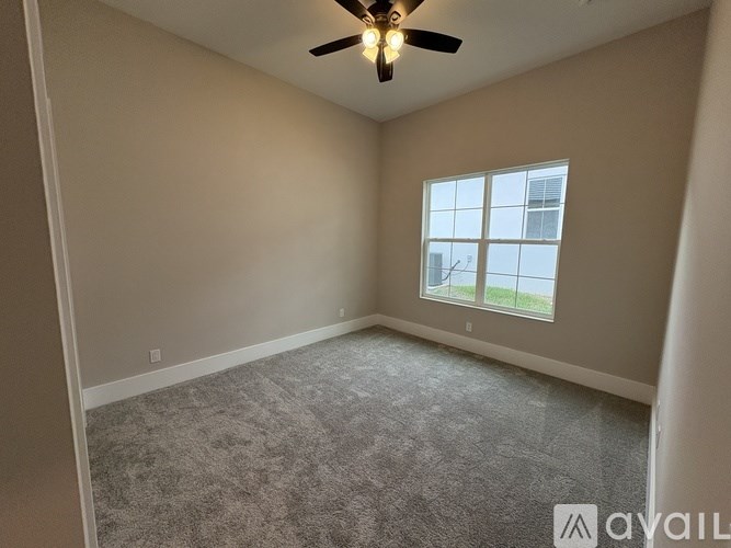A room with a ceiling fan and a window overlooking a building.