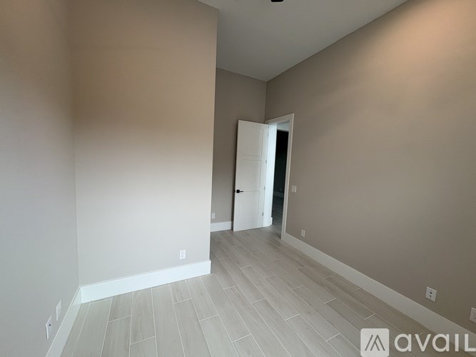 A room with a white door and light grey walls.