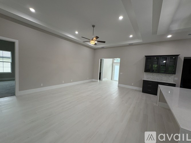 A spacious room with a ceiling fan and lighting fixtures.