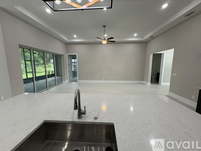 A modern kitchen with a sink, faucet, and a ceiling fan.