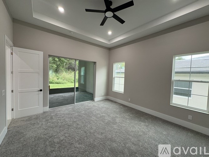 A spacious room with a ceiling fan and sliding glass doors leading to a balcony.