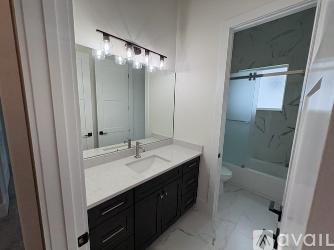A bathroom with a sink, mirror, and shower.