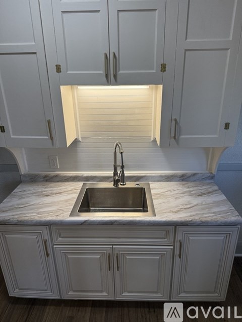 A kitchen with white cabinets and a marble countertop.