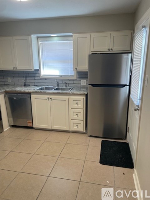 A kitchen with white cabinets and a stainless steel refrigerator.