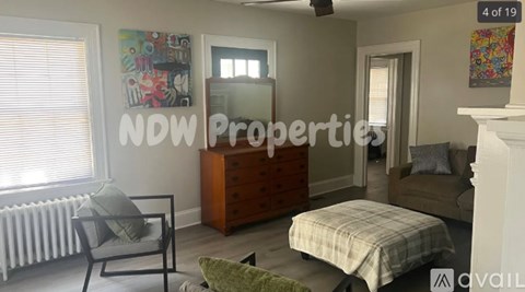 A bedroom with a bed, chair, and a dresser with a mirror above it.
