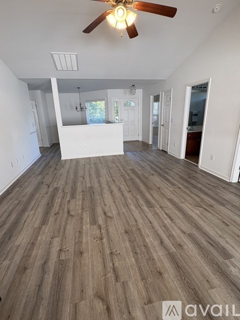 A spacious room with wooden flooring and a ceiling fan.