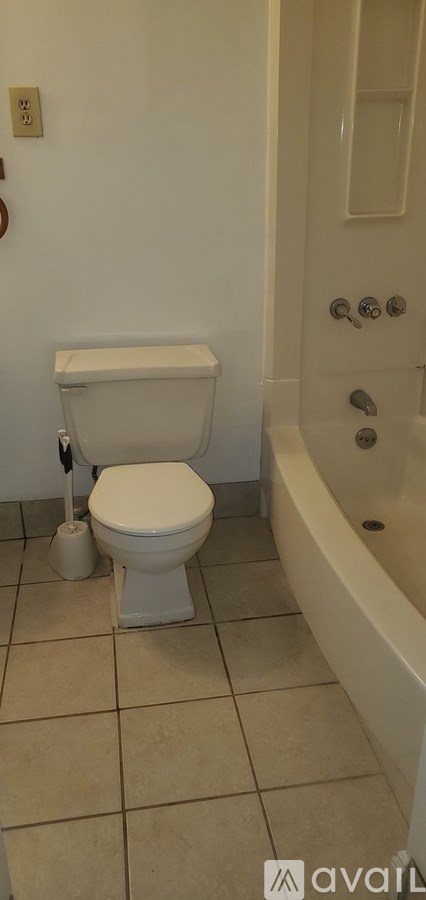 A white toilet sits next to a bathtub in a bathroom.